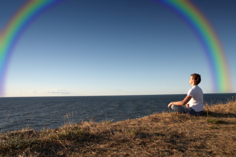 man meditating with a rainbow